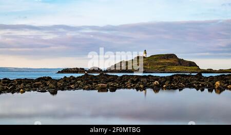 Fidra Island und Leuchtturm am Horizont mit felsigen Ufer und Gezeitenbecken Wolke Reflexionen, Yellowcraig, East Lothian, Schottland, Großbritannien Stockfoto