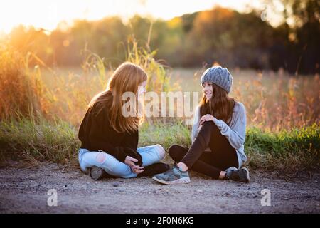 Zwei schöne junge Tween Mädchen in Pullover sitzen draußen im Herbst. Stockfoto