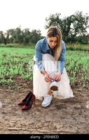 Die junge Frau wechselt ihre Schuhe, während sie auf einem Stuhl sitzt Im Feld Stockfoto