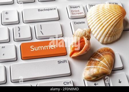 Orangefarbene Taste mit Sommerwort und Muschelschalen auf weißer pc-Tastatur. Sommersaison Urlaub am Meer, Urlaub und Reisekonzepte. Nachricht auf ENTER-Taste. Stockfoto