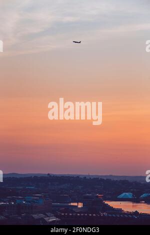 Ein Flugzeug hebt während des Sonnenaufgangs über die Stadt Boston, MA ab. Stockfoto