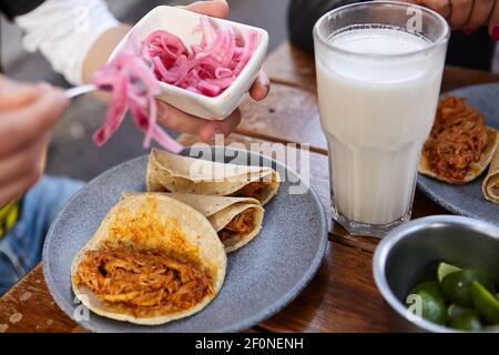 Unkenntlich Mann setzen rote Zwiebel und Zitrone in seine Tacos Stockfoto