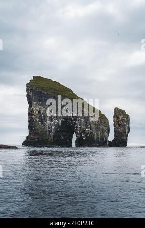 Nahaufnahme der berühmten Drangarnitr Klippe mit den Tindholmur Inseln in Der Hintergrund wurde während der morgendlichen Wanderung im Frühjahr aufgenommen Färöische Küste Stockfoto