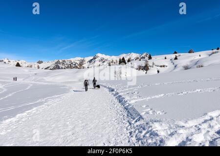 Wanderer auf einem verschneiten Wanderweg in der Winterlandschaft auf dem Lessinia Plateau, Regional Naturpark. Im Hintergrund der Monte Carega. Italien. Stockfoto