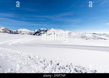 Langlaufloipen auf dem Plateau von Lessinia, Skigebiet Malga San Giorgio. Im Hintergrund die schneebedeckten Gipfel des Monte Carega oder der kleinen Dolomiten. Stockfoto