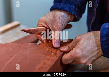 Kunstkonzept. Der Bildhauer modelliert in seinem Architekturstudio die Basis einer Skulptur mit Ton. Stockfoto