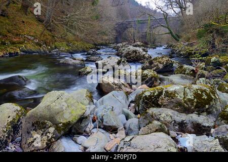 Der Ogwen-Fluss entspringt im Ogwen-See in Snowdonia, ist aber hier in seinem unteren Bereich nahe dem alten Eisenbahnviadukt bei Tregarth zu sehen. Stockfoto