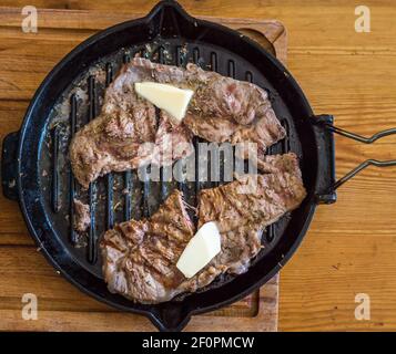 Gebratenes Fleisch in einer Pfanne auf Holzbrett Stockfoto