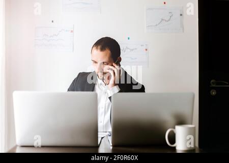 Lächelnder Geschäftsmann, der am Schreibtisch telefoniert Stockfoto