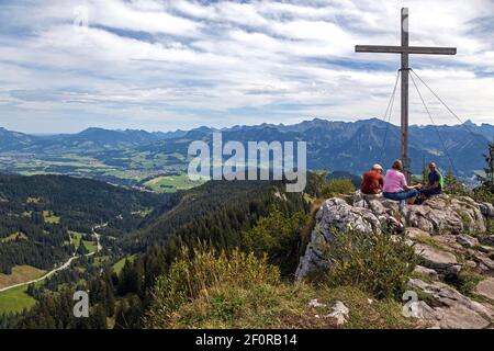 Wanderer machen eine Pause am Gipfelkreuz des Besler mit Blick auf das Illertal und die Allgäuer Alpen, bei Obermaiselstein, Oberallgäu, Allgäu Stockfoto