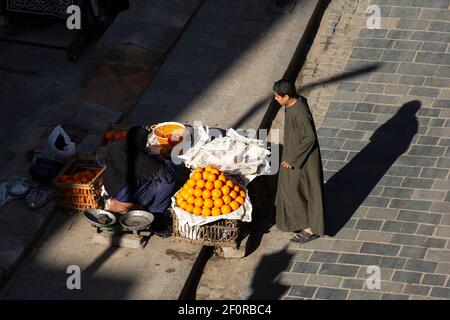 Ein Einheimischer kauft Orangen von einem Straßenhändler am Straßenrand in der Nähe von Zuwayla Gate, Kairo, Ägypten Stockfoto