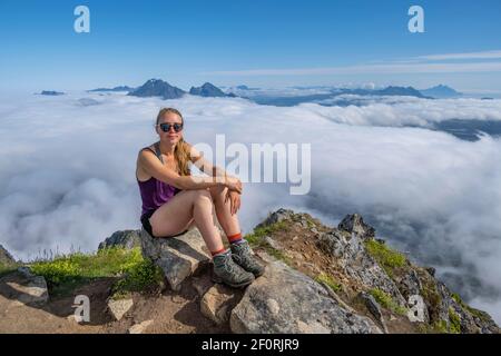 Wanderer, die eine Pause machen, Berglandschaft im Nebel, Blick von der Spitze des Stornappstinden, Lofoten, Nordland, Norwegen Stockfoto