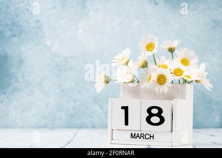 White Cube Kalender für märz mit Gänseblümchen über geschmückt Blauer Hintergrund mit Kopierbereich Stockfoto