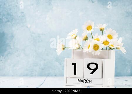 White Cube Kalender für märz mit Gänseblümchen über geschmückt Blauer Hintergrund mit Kopierbereich Stockfoto