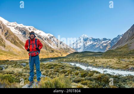 Wanderer auf einem Felsen, Hooker Valley mit Blick auf den schneebedeckten Mount Cook, Hooker River, schneebedeckten Mount Cook National Park, Southern Alps Stockfoto