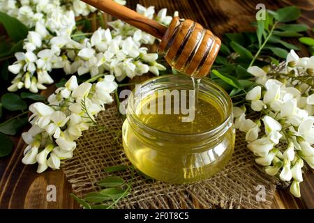 Honig und Akazienblumen auf dem rustikalen Holzhintergrund Stockfoto