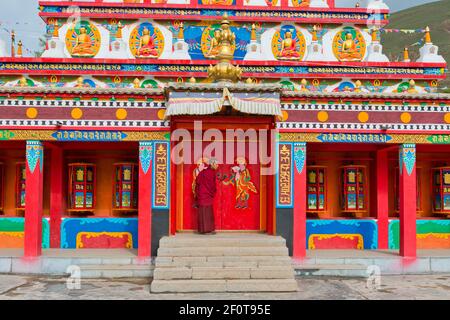 Tibetischer Buddhismus, tibetischer Mönch bei neuen großen bemalten und vergoldeten Stupa, Stupa bei Wutun Si Kloster, Tongren, Repkong, Qinghai, früher Amdo, Tibet Stockfoto