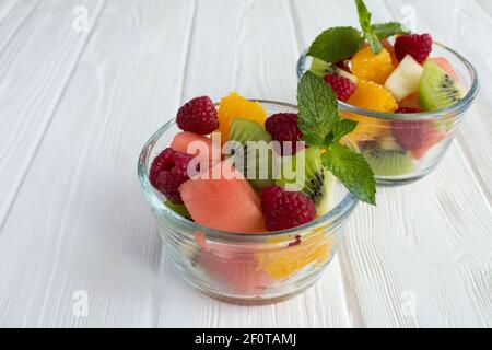 Zwei kleine Glasschüsseln mit Obstsalat auf der weißen Holzhintergrund Stockfoto