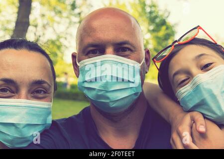 Familie in schützenden medizinischen Masken. Mutter, Vater, Tochter schützen sich vor dem Virus Coronavirus. Familie in medizinischen Masken im Freien. Nahaufnahme Stockfoto