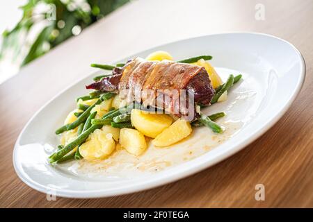 Gekochte Speisen auf einem weißen Teller - Schweinefilet mit BH, Pinienkernen und Frühlingszwiebeln. Stockfoto
