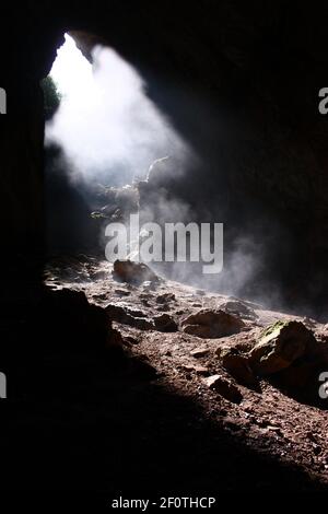 Ausgang aus einer dunklen Höhle, ein herabfallender Lichtstrahl Stockfoto