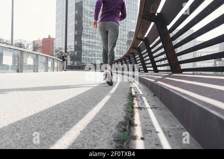 Frau von hinten trägt Sportkleidung und läuft auf Asphalt auf der Straße Stockfoto