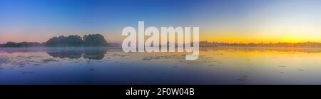 Panorama mit schönem nebligen Sonnenaufgang über Waldsee Stockfoto