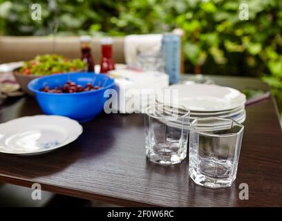 Verschwommenes Bild von leeren Gläsern auf dem Tisch im Restaurant im Freien. Feiertage, Geburtstagsfeier und Dekorationskonzept Stockfoto