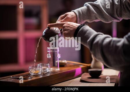 Ein Mann verwöhnt einen Gast mit authentischem reifen vietnamesischen Tee auf einem speziellen gongfu-Brett aus Bambus. Traditionen des östlichen Teetrinkens. Stockfoto