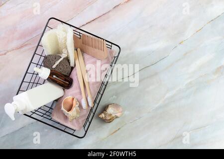 Set von Duschzubehör in einem Korb auf einem Marmorboden. Enthält Flaschen von Kosmetika, Loofa, Zahnbürsten, Handtuch. DIY Öko-Kosmetik. Konzept z Stockfoto
