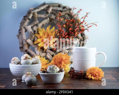 Cappuccino-Kuchenbällchen, Kaffee aromatisierte Trüffel wie Dessert, dekoriert mit Herbst orange Blumen auf einem Holztisch mit weißen Keramik-Kaffee-Tasse und bo Stockfoto