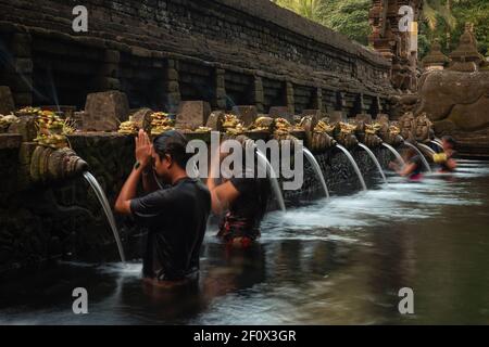 Hinduistische balinesische Pilger beten und baden im Tirta Empul Tempel der Heiligen Quelle in der Nähe der Stadt Tampaksiring in Bali, Indonesien. Stockfoto