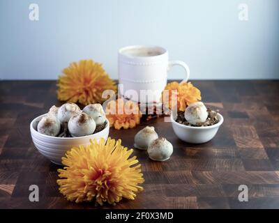 Cappuccino-Kuchenbällchen, Kaffee aromatisierte Trüffel wie Dessert, dekoriert mit Herbst orange Blumen auf einem Holztisch mit weißen Keramik-Kaffee-Tasse und bo Stockfoto