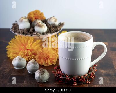 Cappuccino-Kuchenbällchen, Kaffee aromatisierte Trüffel wie Dessert, dekoriert mit Herbst orange Blumen auf einem Holztisch mit weißen Keramik-Kaffee-Tasse und bo Stockfoto