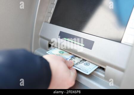 Man's Hand nimmt Geldscheine aus einem Geldautomaten Stockfoto