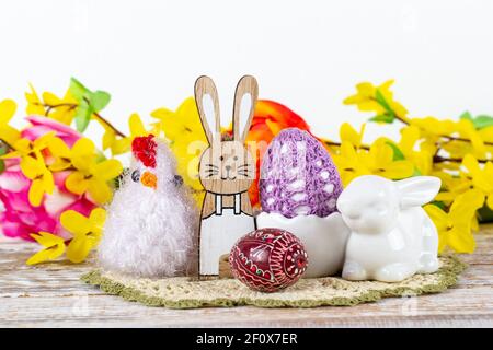 Osterhase, Huhn, Ostereier mit Frühlingsblumen auf einem Holztisch. Stockfoto