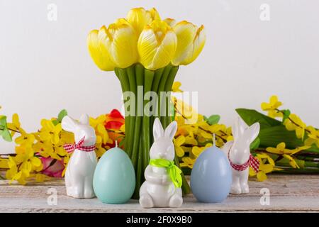 Eine Tulpenförmige Kerze mit Ostereiern, Osterhase und einem Blumenstrauß. Stockfoto