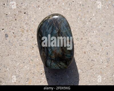 Labradorit Mineralstein auf Betonoberfläche. Stockfoto