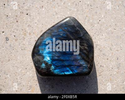 Labradorit Mineralstein auf Betonoberfläche. Stockfoto