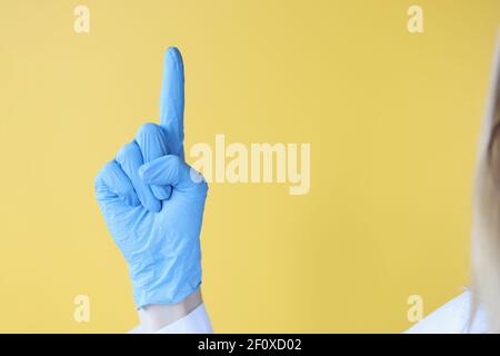 Der Arzt hält den Daumen in einem schützenden medizinischen Handschuh hoch Stockfoto