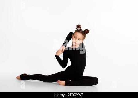 Liebenswert kleines Kind Mädchen in schwarzer Sportbekleidung tun Stretching auf Studio-Hintergrund. Gymnastik Stockfoto