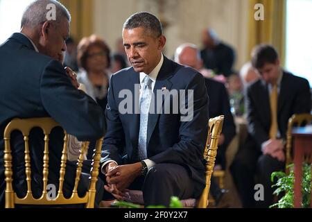 Präsident Barack Obama verneigt den Kopf, während Pastor Joel Hunter das Eröffnungsgebet während des Ostergebetsfrühes im Ostsaal des Weißen Hauses am 14. April 2014 hält. Mit Präsident Obama sitzt Dr. Otis Moss. Stockfoto