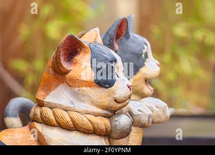 tokio, japan - februar 28 2021: Profilansicht eines aum-Paares aus Holz mit geschlossenen und offenen Maul-Statuen, die japanische Maneki-Neko-Katzen darstellen Stockfoto