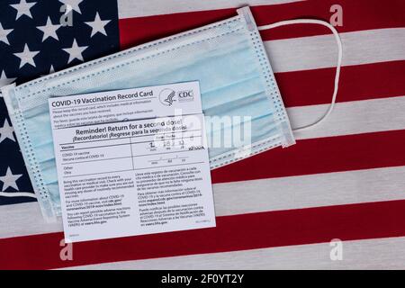 Flourtown, PA - 14. Februar 2021: CDC COVID-19 Impfkarten mit Daten gefüllt, die zeigen, dass beide Seiten auf US-Flagge und Papier ma Stockfoto