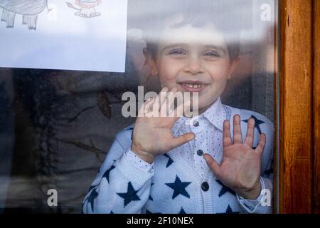 Netter kleiner Junge, der von innen durch das Fenster schaut Stockfoto