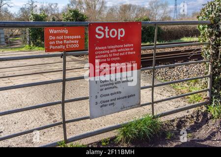 Red Stop Achtung Trespass nicht Warnschild an einem Tor an einem Bahnübergang in England, Großbritannien Stockfoto