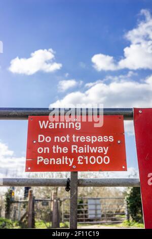 Red Stop Achtung Trespass nicht Warnschild an einem Tor an einem Bahnübergang in Südengland, Großbritannien Stockfoto