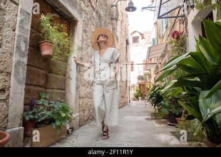 Schöne blonde junge weibliche Reisende tragen Stroh Sonnenhut Sightseeing und genießen Sie Sommerurlaub in einer alten traditionellen Küstenstadt an der Adria Stockfoto