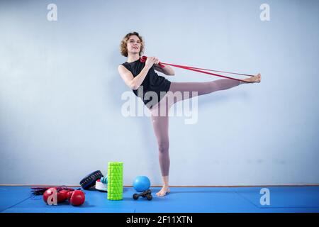 Sportlerin führt Übungen mit Widerstand Band. Menschen, Sport und Fitness. Junge Frau beim Training mit Trainingsband im Fitnessstudio. Aktiver Lebensstil Stockfoto