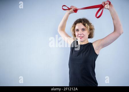 Sport Frau Ausübung mit einem Widerstandsband. Schlanke Mädchen in guter Form. Menschen-, Sport- und Fitnesskonzept. Trainingsbänder trainieren, dehnen Stockfoto